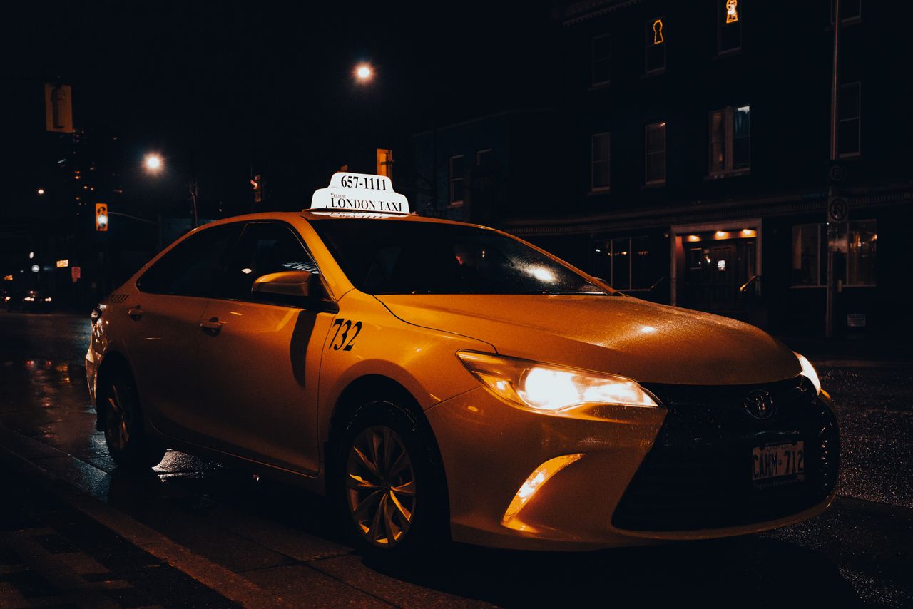 services-01 A yellow taxi waiting at night in London, Ontario, Canada. Urban transportation captured with street lights.