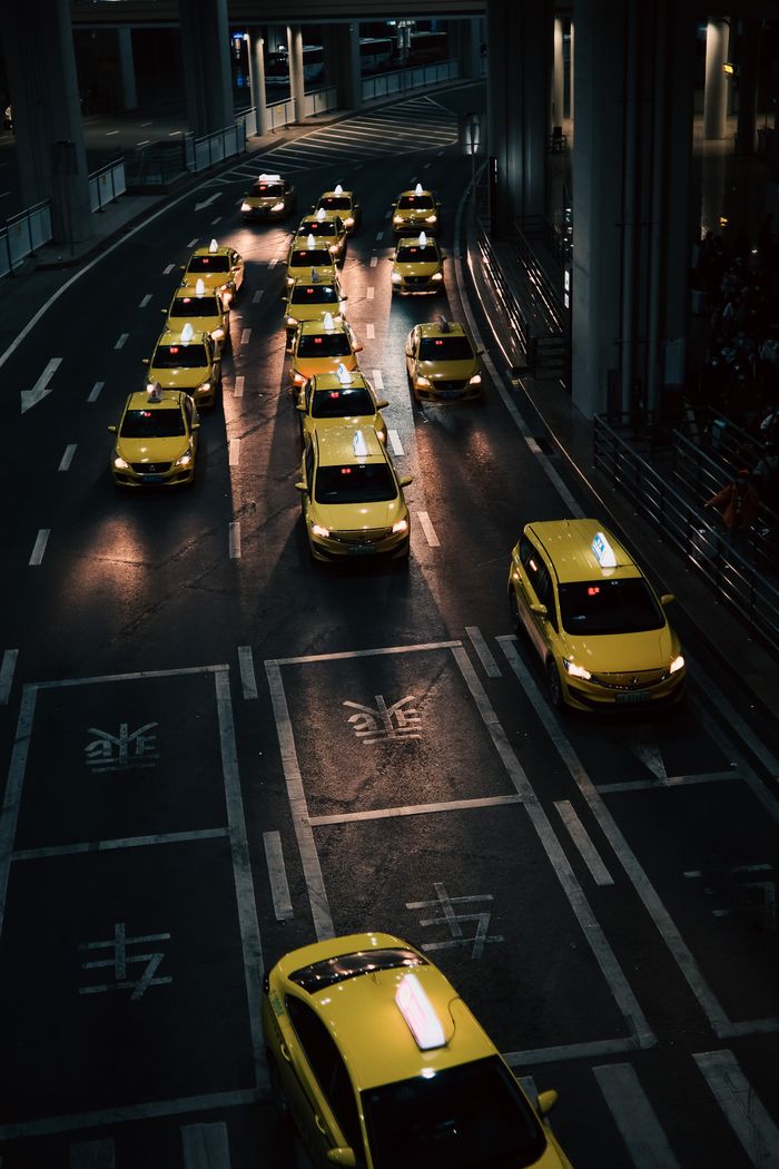 services-02 High angle view of lined yellow taxis on urban street during nighttime.