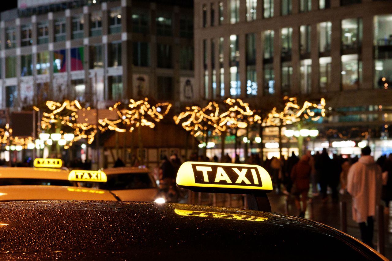 services-03 A vibrant city scene at night featuring taxis with illuminated signs and festive decorations.