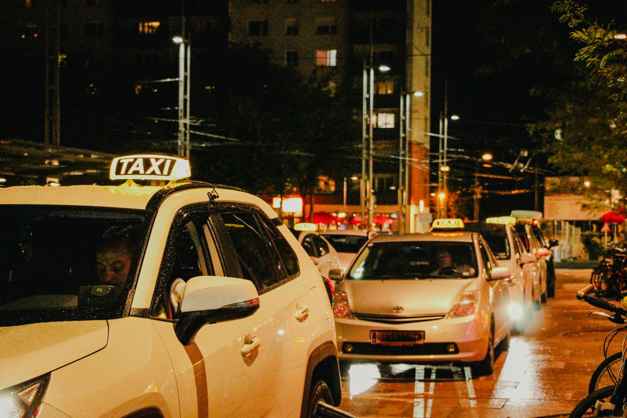 hero-img-02 Taxis lined up under streetlights in Salzburg, Austria, captured at night.