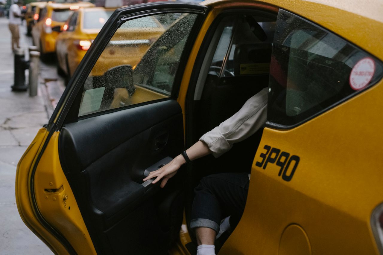 about-02 Anonymous passenger closing door of cab parked on roadside with blurred cars on background in rush hour on street in city
